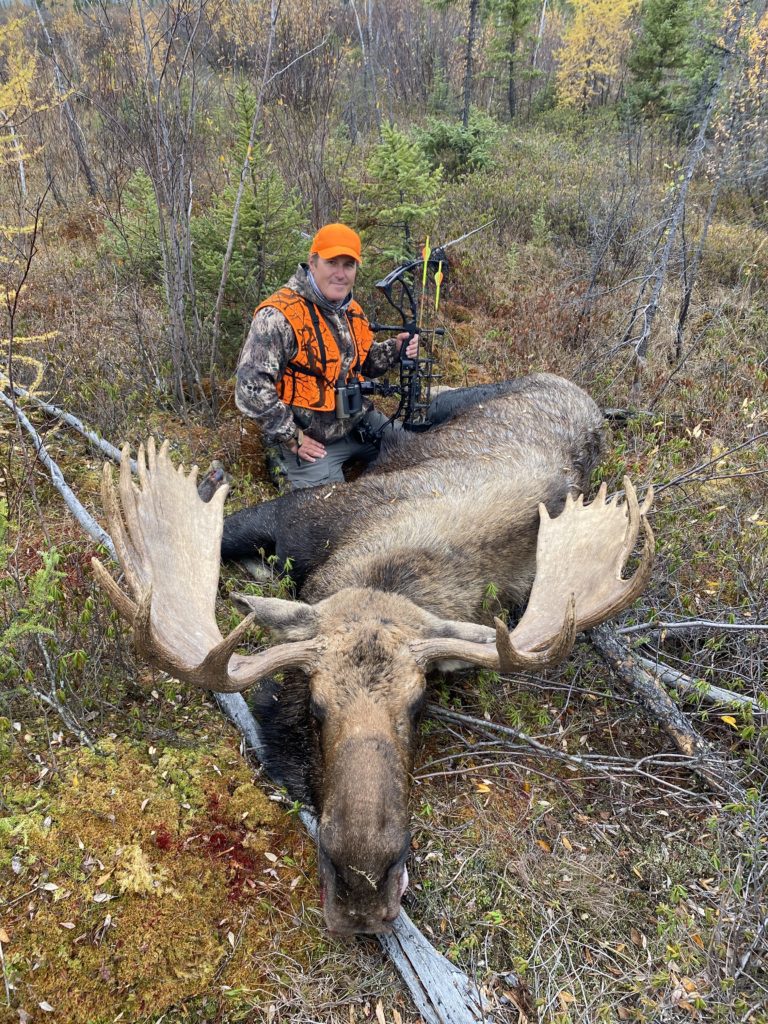 portrait of person standing over a freshly killed moose