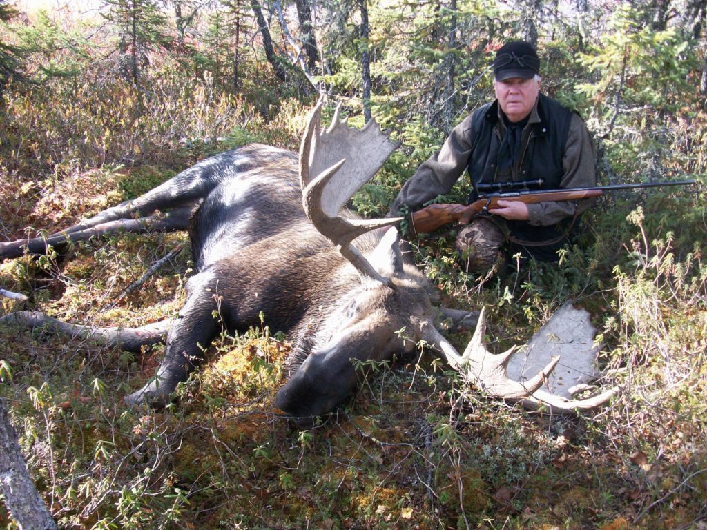 portrait of a man, his gun, and a down moose