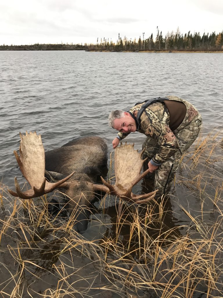 portrait of Kovach with a freshly killed moose laying in water
