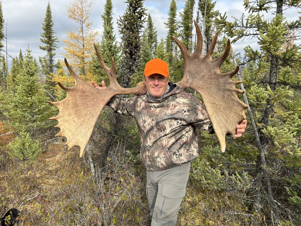 man holding moose antlers on their shoulders