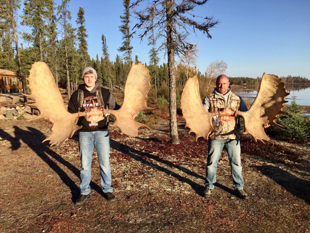 portrait of 2 mention holding their moose antlers