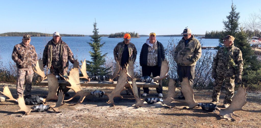 portrait of week 2 of moose hunting and 6 men and 8 moose antlers